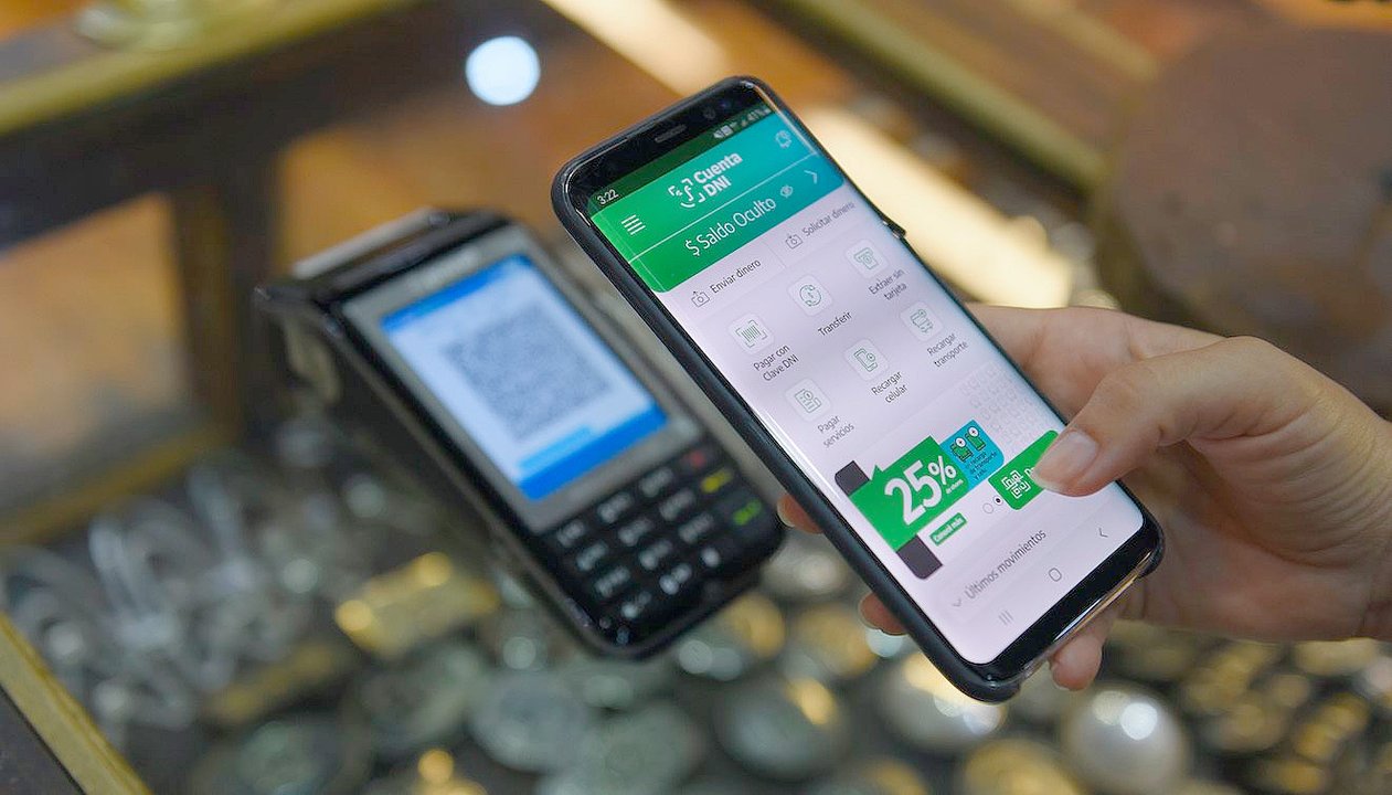 Celular con app de billetera virtual abierta sobre billetes
