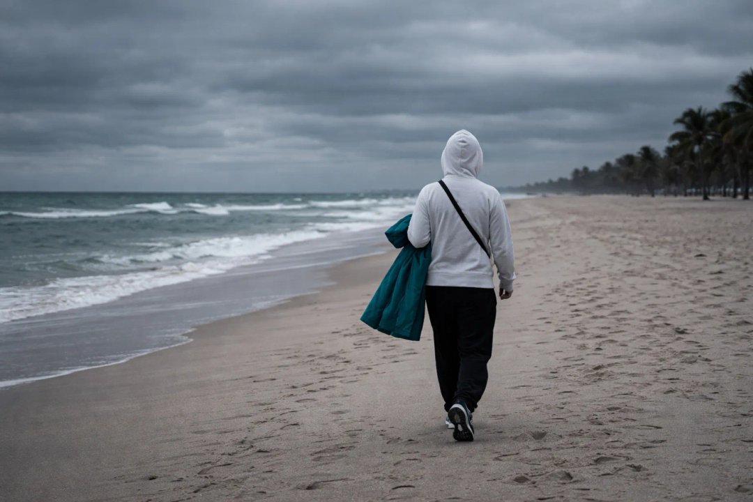 Personas abrigadas caminando en una playa casi vacía de Miami Beach durante una mañana fría