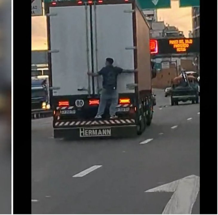 Joven viajando colgado de la parte trasera de un camión en la Autopista 25 de Mayo