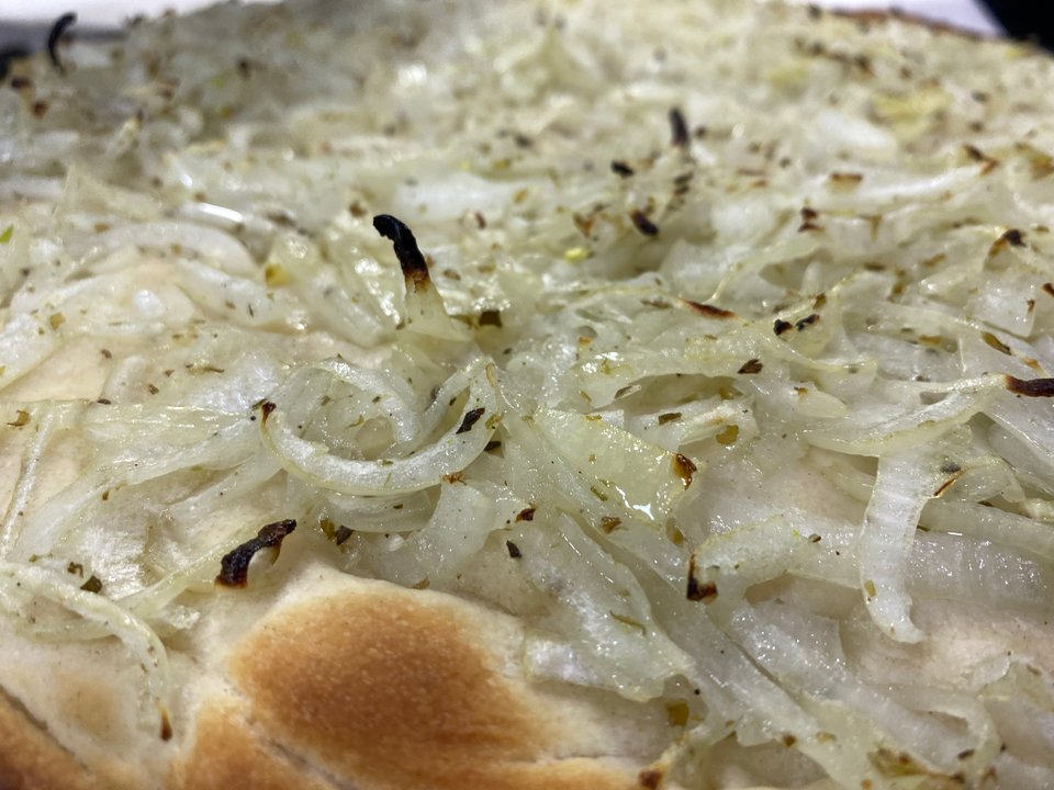 Pizza de fugazza y fugazzetta servidas en una pizzería porteña