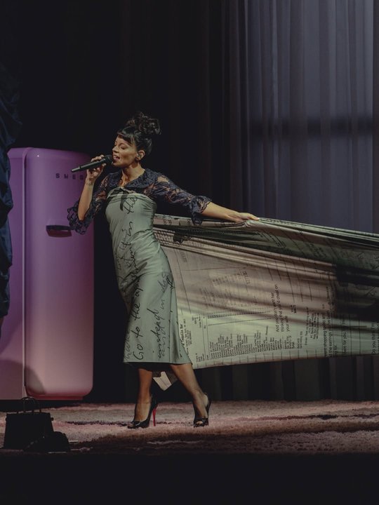 Lily Allen en el escenario con un vestido hecho con tickets de compras