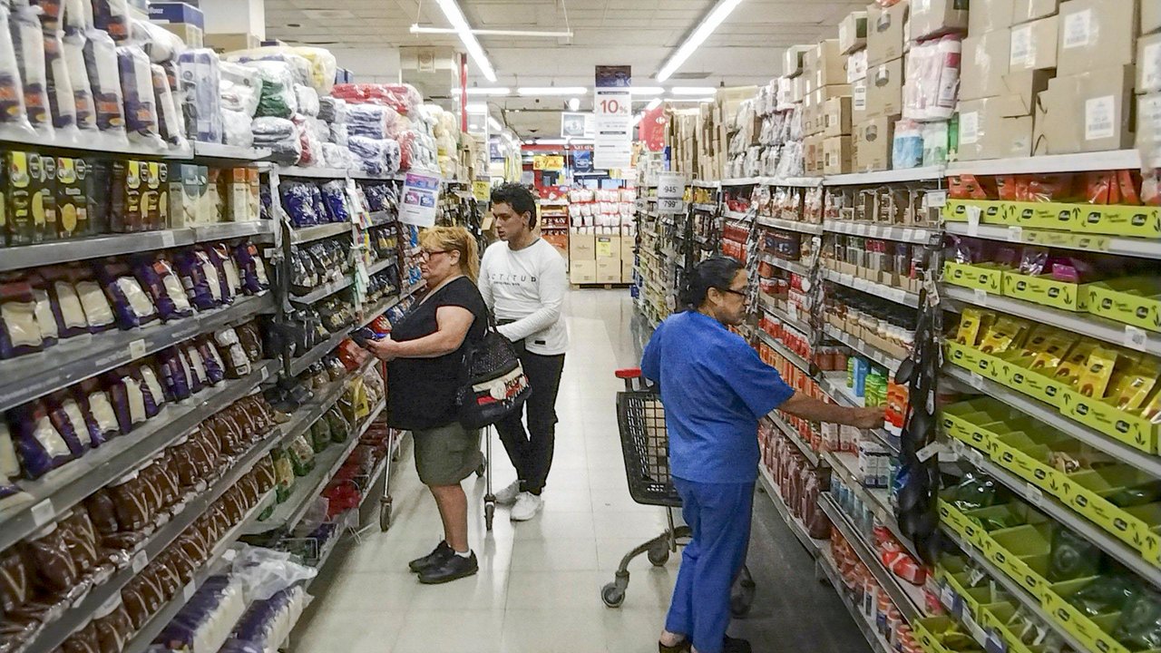 Consumidores frente a góndolas en supermercado