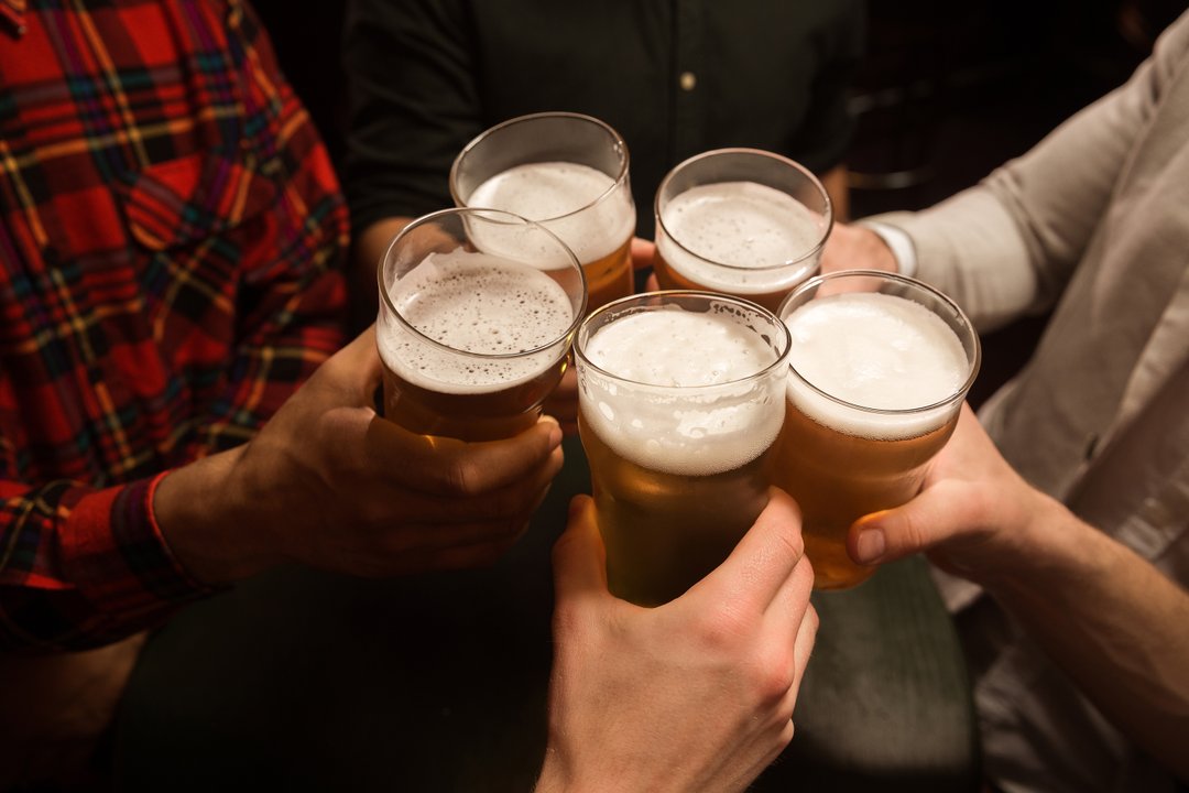 Personas brindando con cerveza en un bar